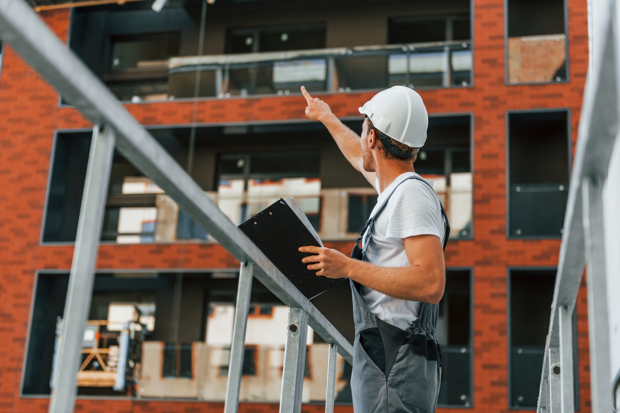 Manager of project. Young man working in uniform at construction at daytime