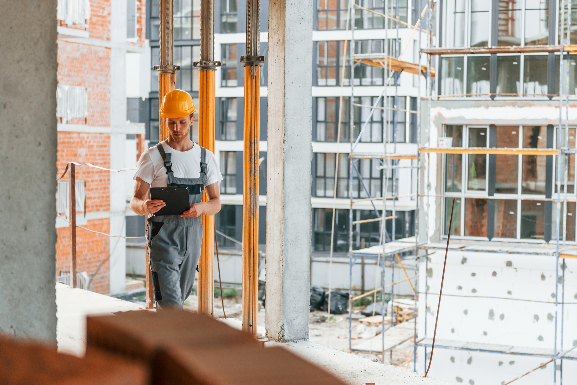 Yellow colored hard hat. Young man working in uniform at construction at daytime